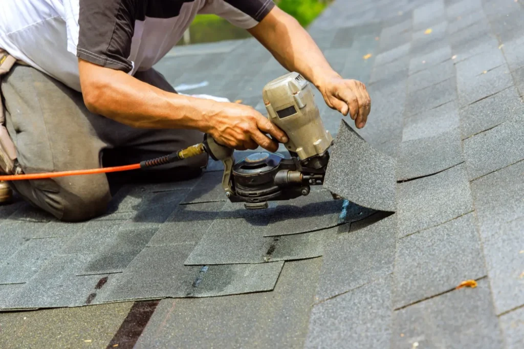 Disaster Masters roofer fastening asphalt shingles with a roofing nailer